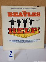 Front cover of The Beatles "Help!" vinyl LP showing the title and band members in black silhouette with semaphore style poses on white background.