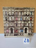 Front cover of Physical Graffiti album shows the New York apartment building with windows having various images, sleeve has some wear.