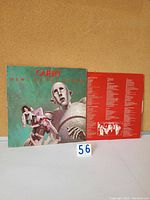Front cover of Queen News of the World vinyl LP showing robot holding band members with visible wear on corners.