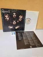 Front side of Queen II gatefold cover with record sleeve and lyric insert on display.