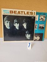 Front album cover of 'Meet The Beatles' showing four band members in black and white with title text.