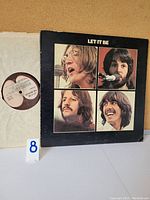 Front cover of The Beatles Let It Be vinyl LP showing close-up portraits of band members in black background.
