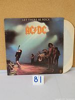 Front of the album cover featuring AC/DC band on stage with 'Let There Be Rock' and AC/DC logo prominently displayed.