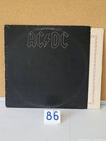 Front view of the black AC/DC Back in Black vinyl record sleeve, showing moderate wear and surface marks.