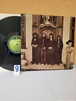 Front cover of The Beatles Again vinyl album showing the four band members standing in front of a large ornate door.