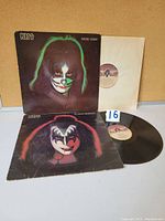 Two KISS vinyl LPs with Peter Criss and Gene Simmons face makeup on sleeves and vinyl partially visible
