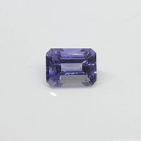Close-up image of the rectangular violet-blue Iolite gemstone on a white background highlighting cutting and color.