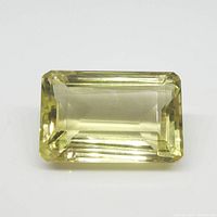 Clear rectangular yellow citrine gemstone on white background emphasizing facets and clarity.