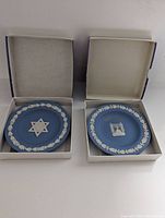Two Wedgwood Jasper Blue round sweet dishes inside their original boxes displaying Judaica designs: one with Magen David and Hebrew word; the other with gold print commemorating Israeli independence.