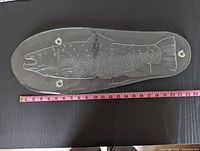Clear thick glass fish-shaped serving platter with etched rainbow trout design, three visible glass feet shown, tape measure for size reference.