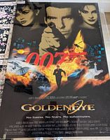 Photo of the GoldenEye movie poster inside thick protective plastic, showing the vibrant artwork, text, and overall very good condition.