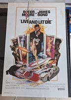 Full view of the colorful original 1973 movie poster for Live and Let Die featuring Roger Moore as James Bond with a collage of images and bold text.