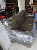 Front corner angle showing three back and seat cushions, leather upholstery and arm shape