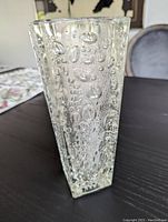 Angled side photo showing the thick clear glass vase with bubble texture on the outside and square shape.