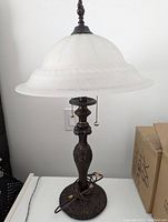 Photo of one lamp showing frosted glass shade with clean surface, heavy metal stand and base with Art Nouveau motifs, and two pull chains hanging below the shade.