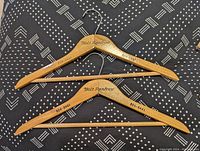 Photo showing two Holt Renfrew wooden hangers with printed phone number 924-8441, light brown wood, smooth finish