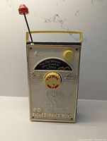 Front view of vintage Fisher Price Music Box TV Radio with visible wear and 'The Old Woman Who Lived in a Shoe' motif.