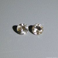 Two loose round champagne morganite gemstones placed side by side on a gray surface, showing their reflective facets.