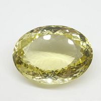 Oval cut yellow citrine gemstone shown from above on a white background.