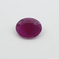 Close-up image of oval faceted ruby gemstone showing color and facets.