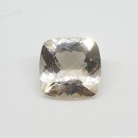 Close-up photo showing the faceted square cushion cut champagne colored morganite gem against a white background.