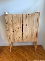 Front view of closed natural pine wood cabinet, showing two doors and wood grain details.