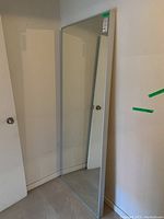 Full-length rectangular floor mirror leaning against the wall showing full frame and reflective surface.