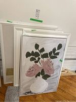 Front view showing framed floral abstract painting and two white frames stacked behind, with some floor visible.