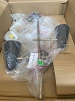 Kichler 2-light wall sconce in box, wrapped in plastic, showing metal frame and two black shades.