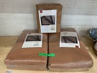 Three new Loloi Premium Grip beige rug pads still sealed in packaging, stacked on a wooden surface.