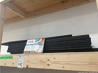 Stack of 10 black Secure Step stair treads on a wooden shelf with product label visible.