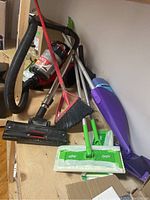 View of Dirt Devil Featherlite vacuum and assorted cleaning tools including brooms, mops, dustpan, and handheld vacuum.