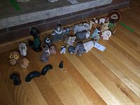 Top view showing a large collection of various small animal figurines arranged on a hardwood floor. Includes owls, zebras, bears, lions, foxes, and abstract shapes.