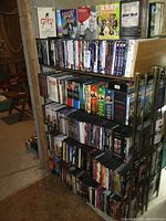 Front view of metal shelving unit with four shelves filled with DVDs and top holding DVD box sets