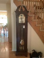 Full view of tall wooden grandfather clock in situ, showing entire case and base.