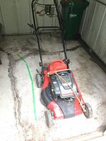 Front side view of red and black Snapper lawn mower showing the handle and four wheels.