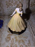 Back view of the Elizabeth Royal Doulton figurine in a yellow dress showing details of the gown and hair.