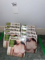 Nine unopened packages of WonderBra 2620 bras arranged on carpet, showing front packaging with model image and size information.