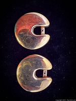 Obverse view of both earrings laid flat on black background