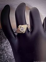 Top view of ring on black display hand showing hexagonal bezel and round diamond