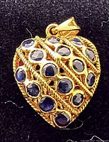 Front view of heart-shaped pendant showing 15 round blue sapphires set in 14kt yellow gold with rope-detailing