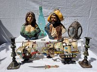 Overall view of the six items including two chalkware busts, two model ships, decorative sword, and brass candlesticks