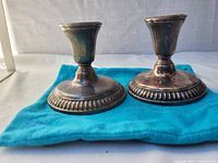 Pair of silver plated Birks candlestick holders on blue cloth showing front side and patina.