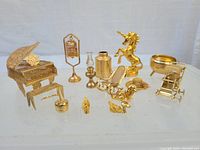 Full collection of metallic gold dollhouse furniture miniatures with various shapes and types, including piano and birdcage.