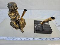 Photo of two vintage pen holders: one with a bronze cherub figure playing flute with brass pen holder, and the other a simple black marble base with brass pen holder.