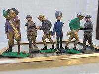 Front row display of seven painted metal toy figures depicting soldiers and a pirate. Figures have worn paint with visible chipping and scratches indicating aged and battle-worn condition.