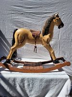 Front side view of wooden rocking horse showing detailed painting and saddle