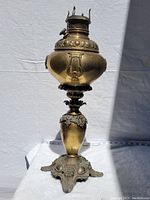 Full view of the Victorian parlour lamp showing the upper oil reservoir and decorative elements with a base measuring tape visible.