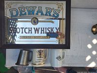 Framed Dewar's Scotch Whisky bar sign with reflection visible