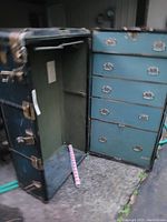 Opened steamer trunk showing wardrobe section with drawers inside and green fabric lining